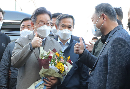 더불어민주당 이재명 대선후보가 26일 오전 전남 목포시 동부시장을 방문, 시장 관계자로부터 꽃다발을 받은 뒤 엄지손가락을 들고 있다.  연합뉴스